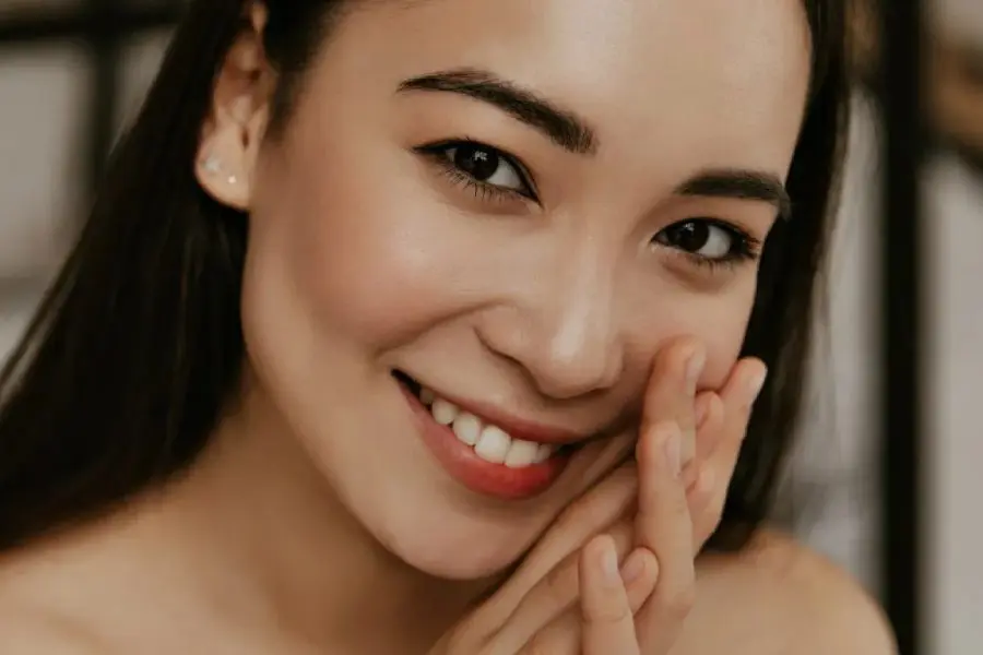 Smiling black-haired woman with her hands clasped near her face