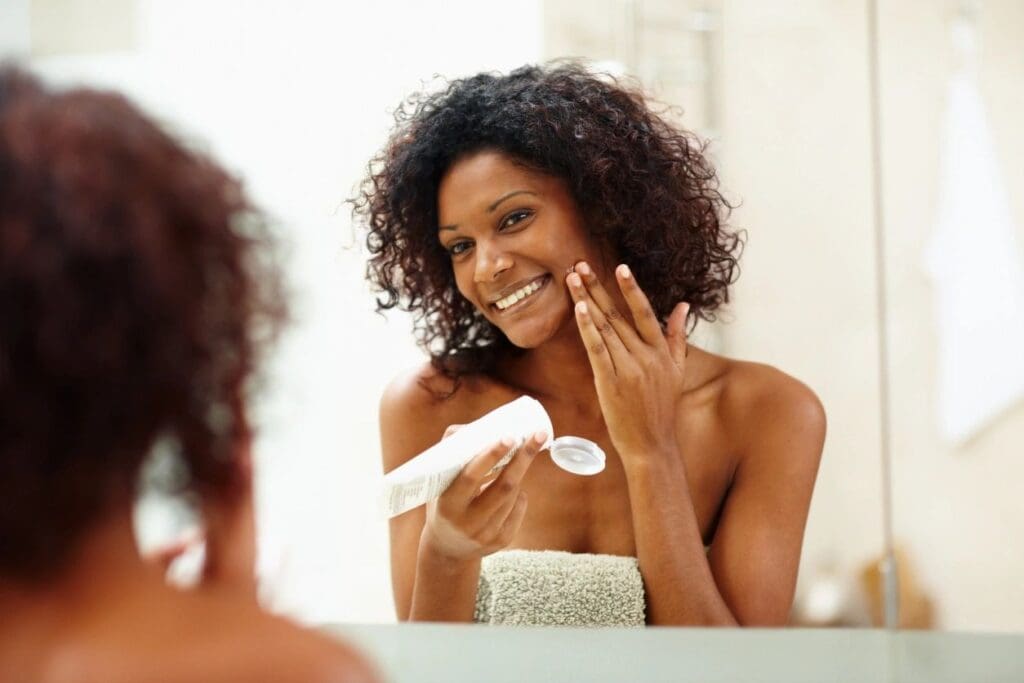 A Woman of color Applying Cream on the Face