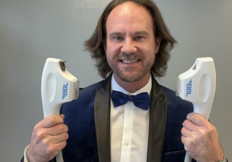 Smiling man in tuxedo holding BBL devices