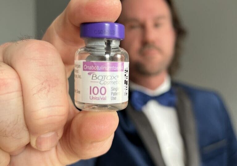 Man in suit holding Botox vial