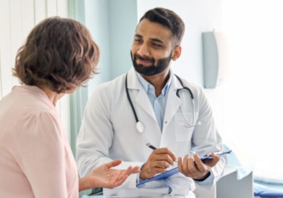 Smiling male doctor taking notes with patient