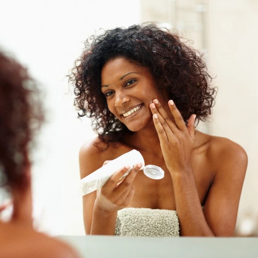 A Woman of color Applying Cream on the Face