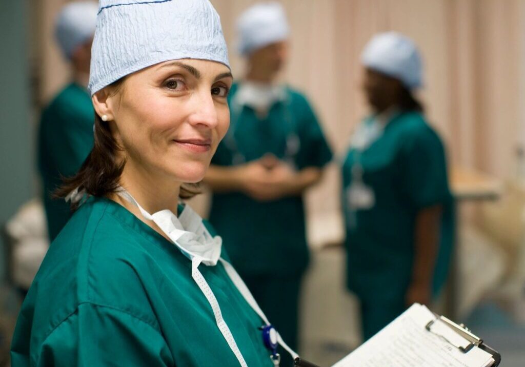 Smiling nurse with clipboard in hospital setting.